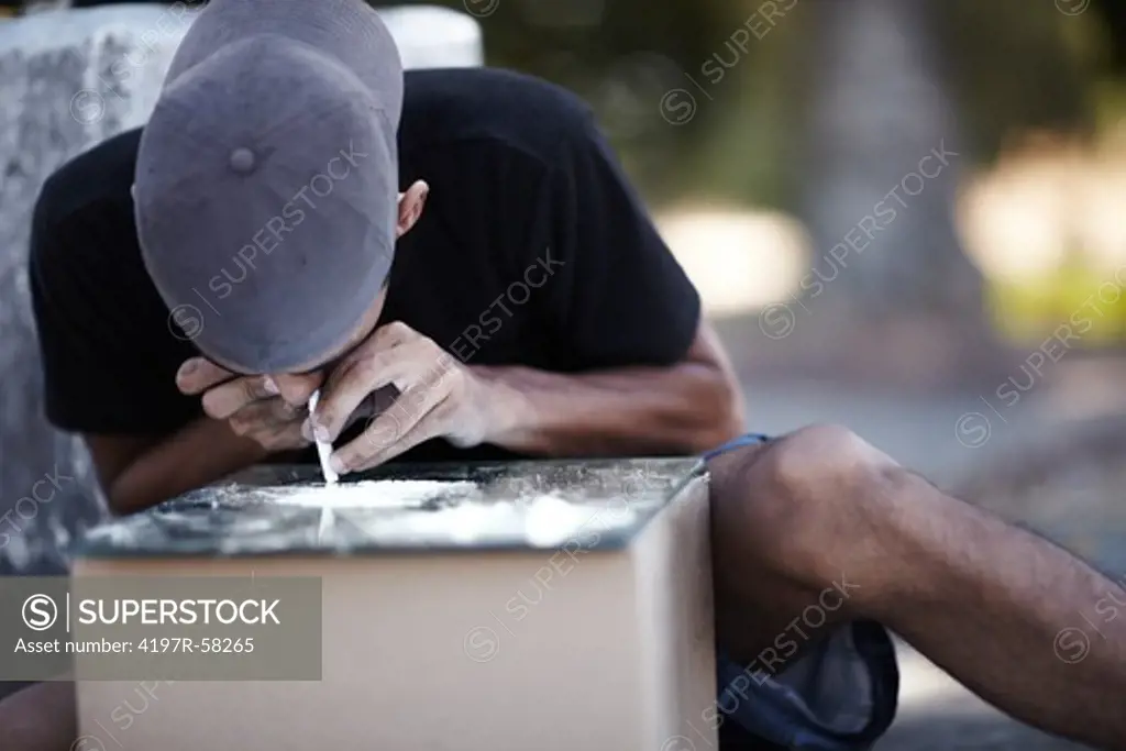 A man snorting cocaine off of a mirror on a box