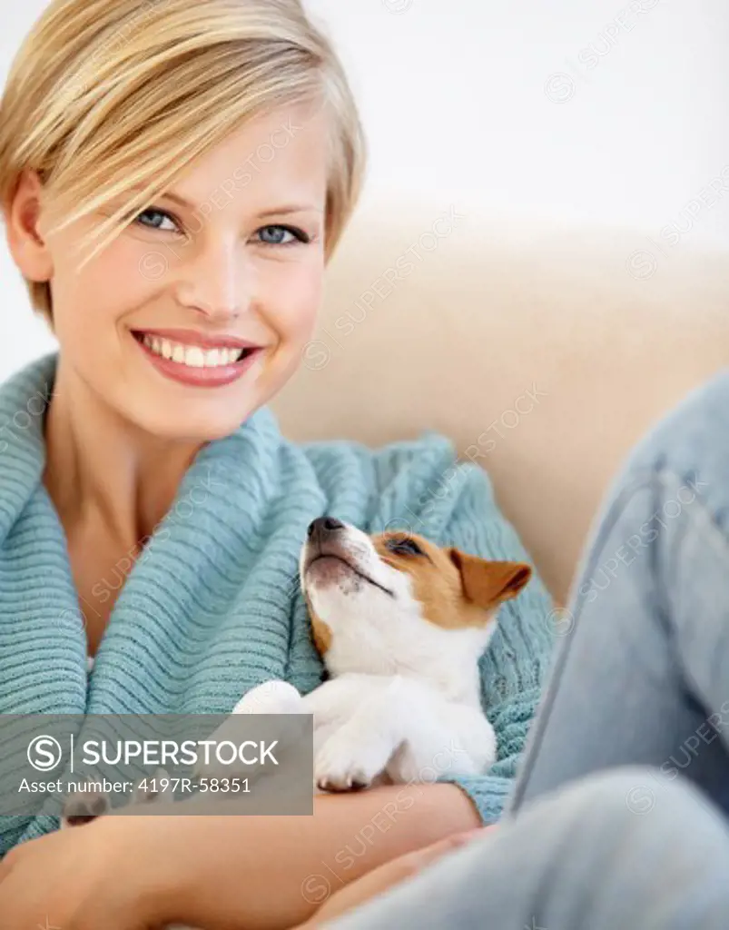 An attractive young female relaxing on the couch with her puppy