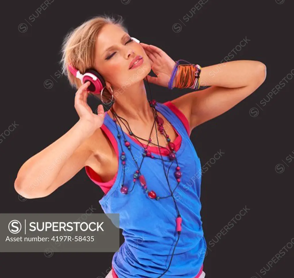 Trendy young woman dancing and listening to music against a colorful digitally manipulated background