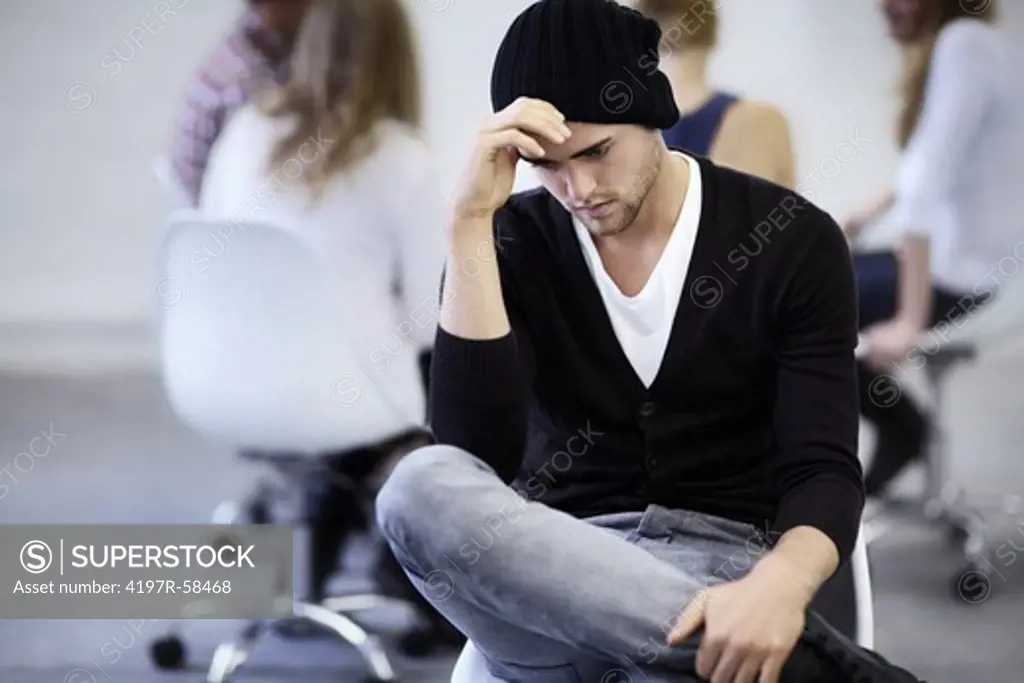 A young man takes a moment alone during a group therapy session