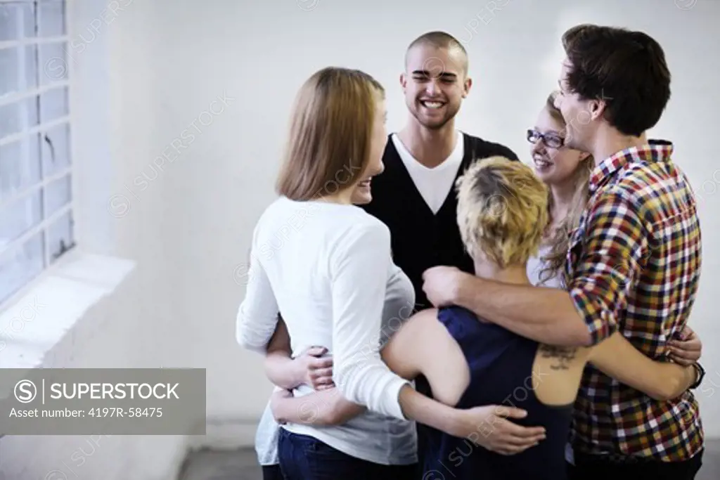 A group of young people embracing happily during a support group session