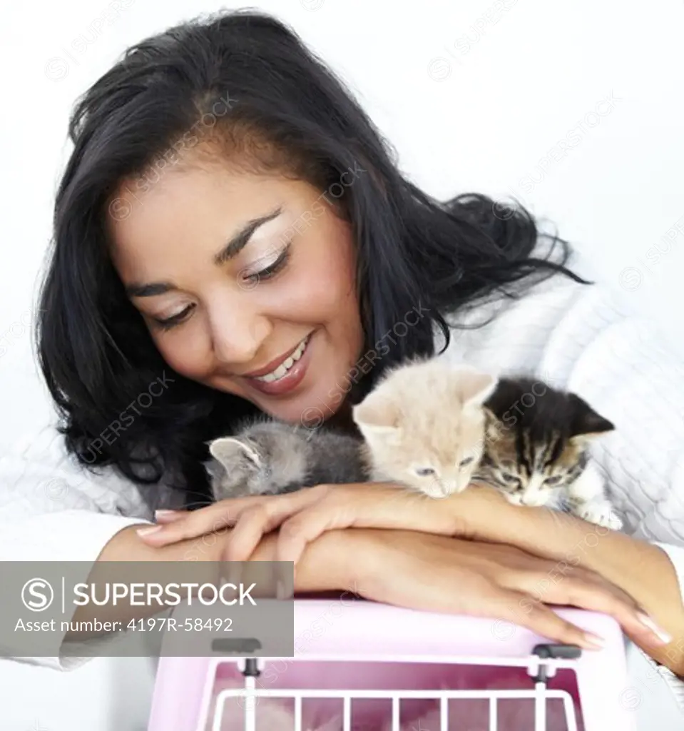 Gorgeous young woman holding three little kittens on top of a pet carry-case