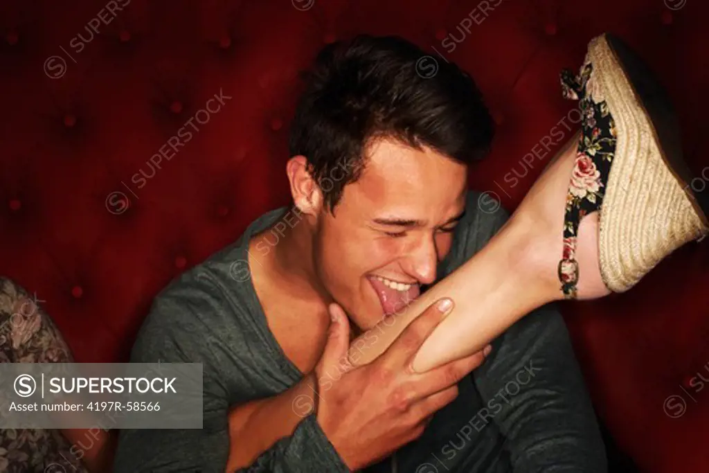 A young guy licking a woman's leg while out on a crazy night of partying
