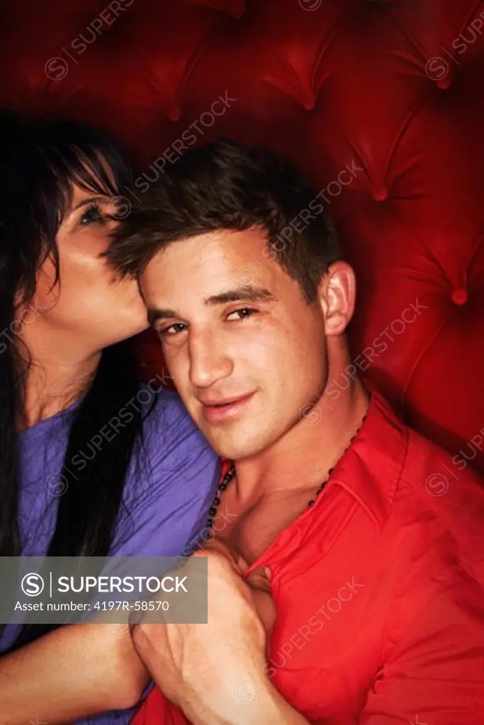 Candid photo of a young guy listening to a girl whispering to him while out partying