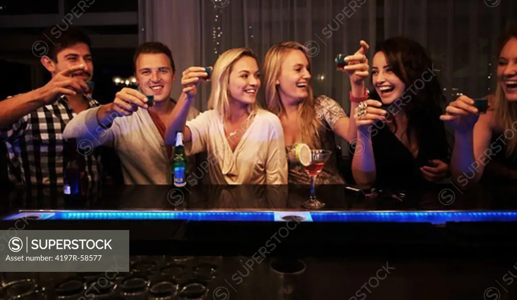 A line of amped up friends getting ready to take shots at the bar