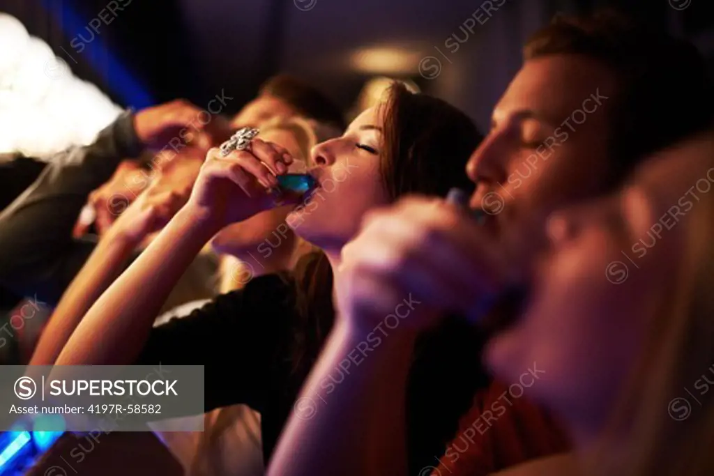 A line of friends taking shots at the bar with their eyes closed