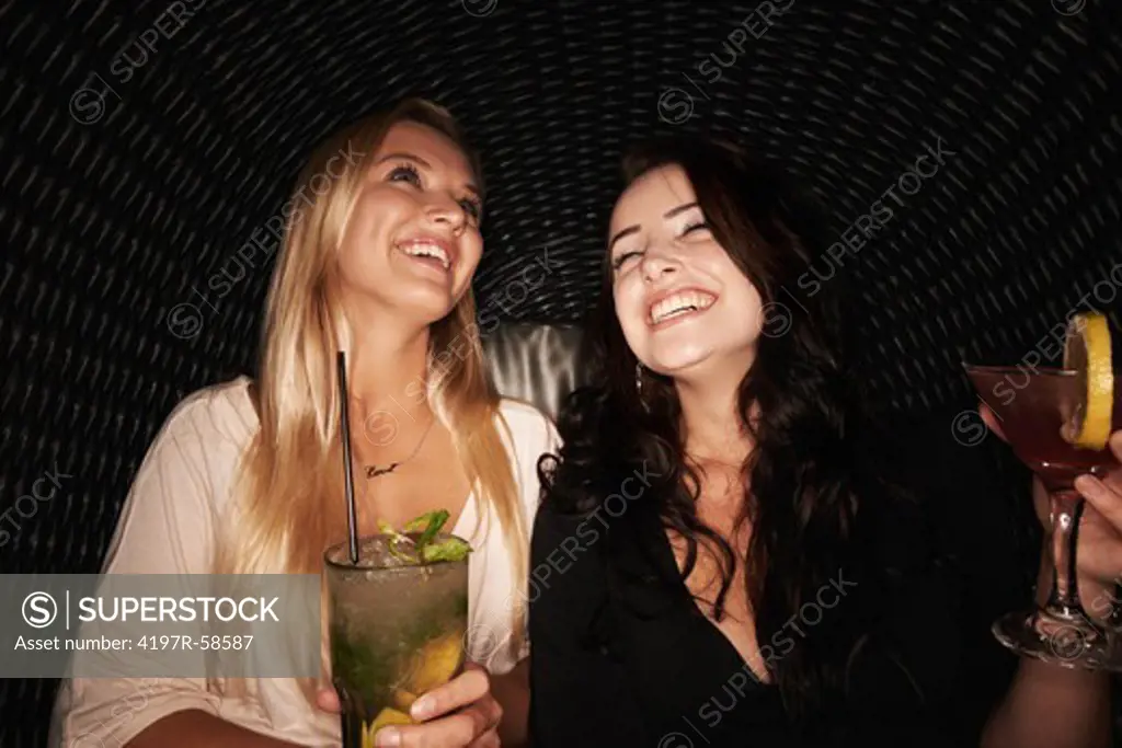 Two pretty young girls enjoying cocktails at a club together