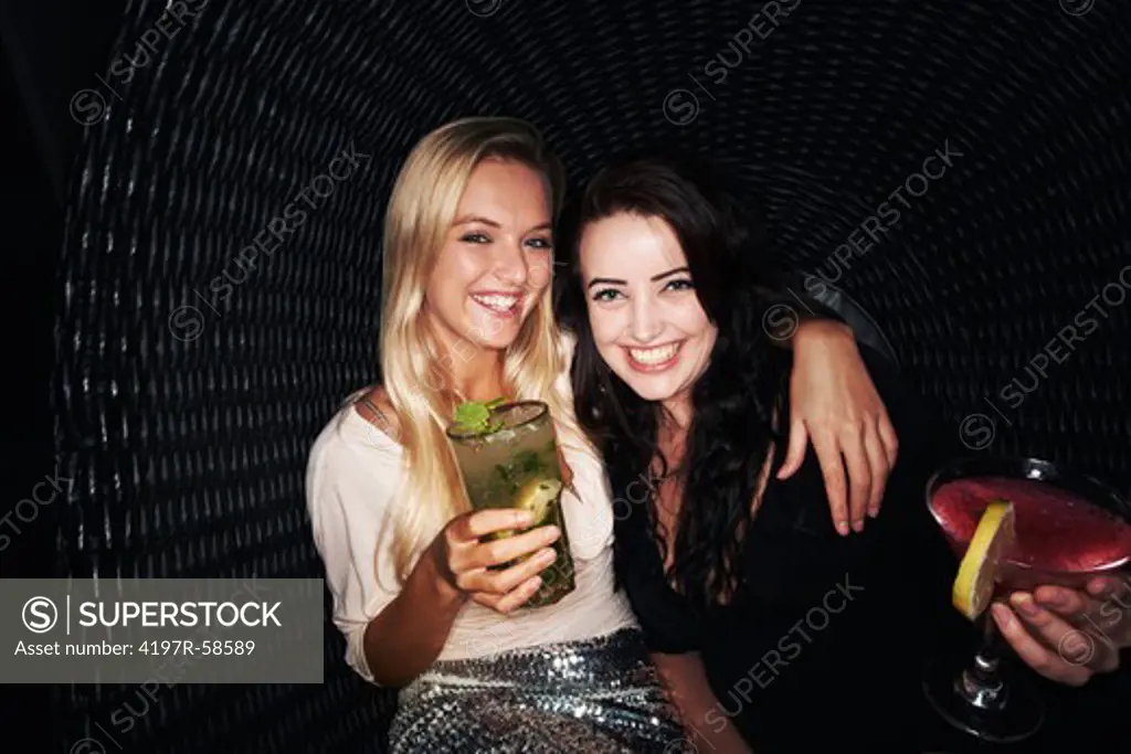 Two pretty young girls drinking cocktails while out partying