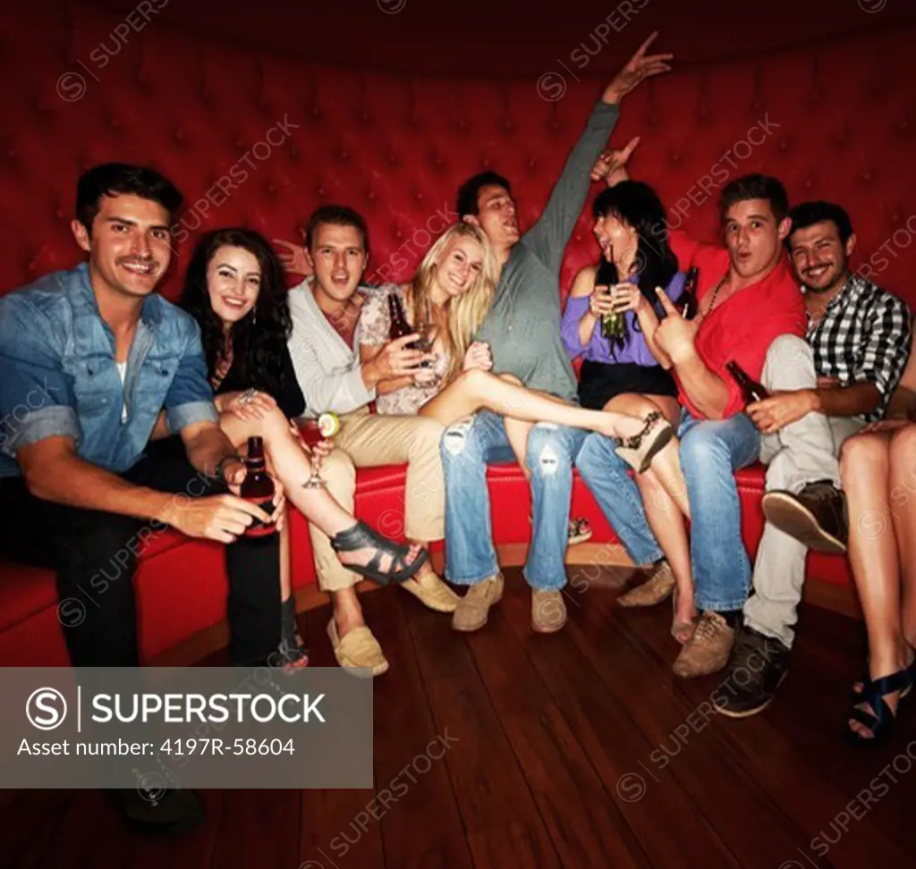 A group of friends enjoying drinks while sitting in a booth at a club