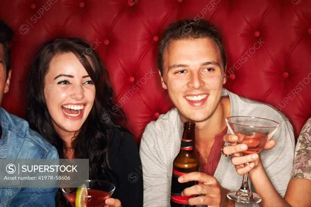 A handsome young guy looking at something while drinking at a club with friends