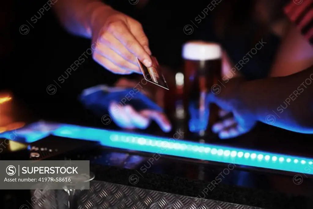 A patron at a club handing the barman a credit card to pay for the round
