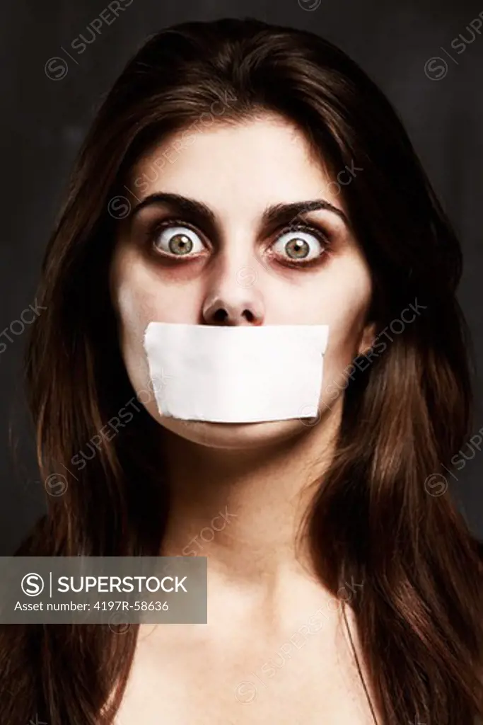 A studio concept shot of a young woman with her mouth taped closed