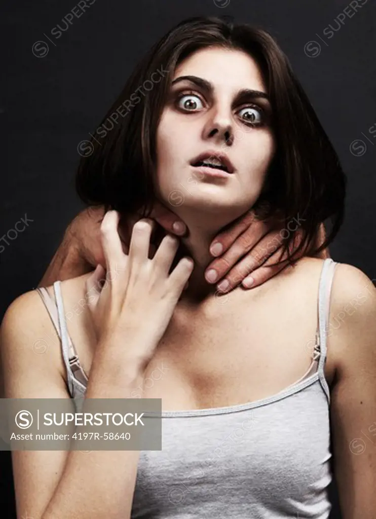 A studio shot concept shot of an emotionally distressed woman being choking from behind by an unseen predator