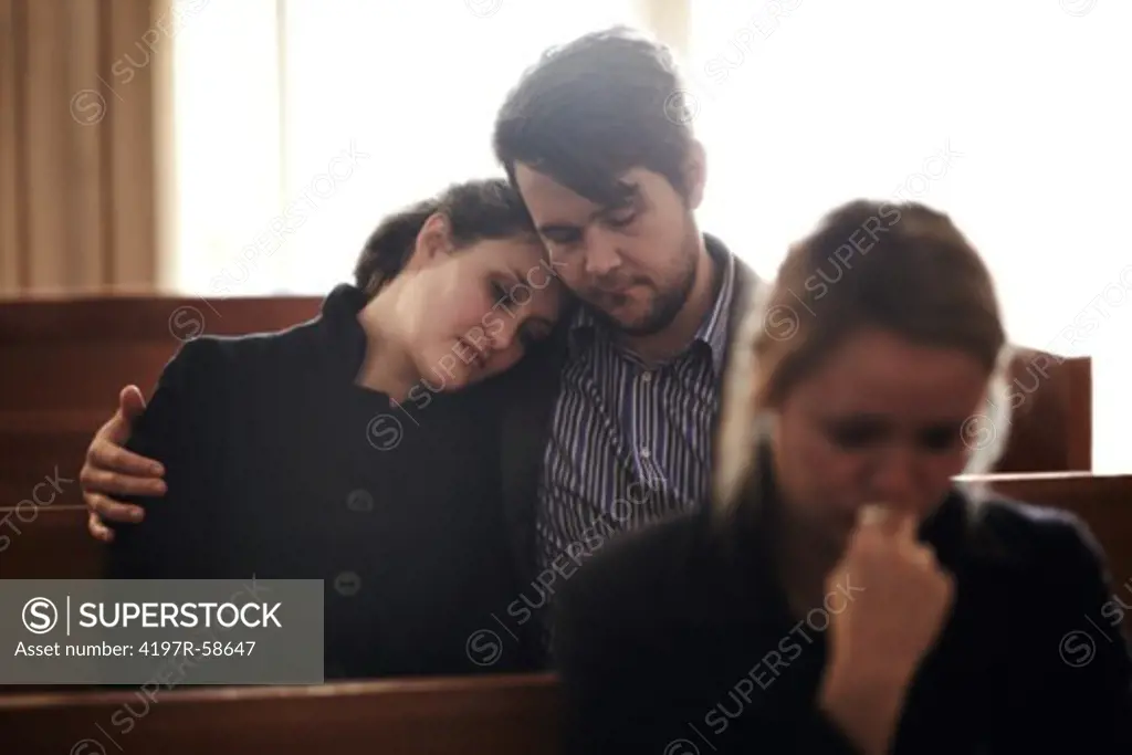 A family crying at a funeral service in a church