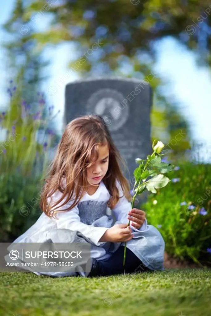 A little girl sitting at the graveside of a deceased family member