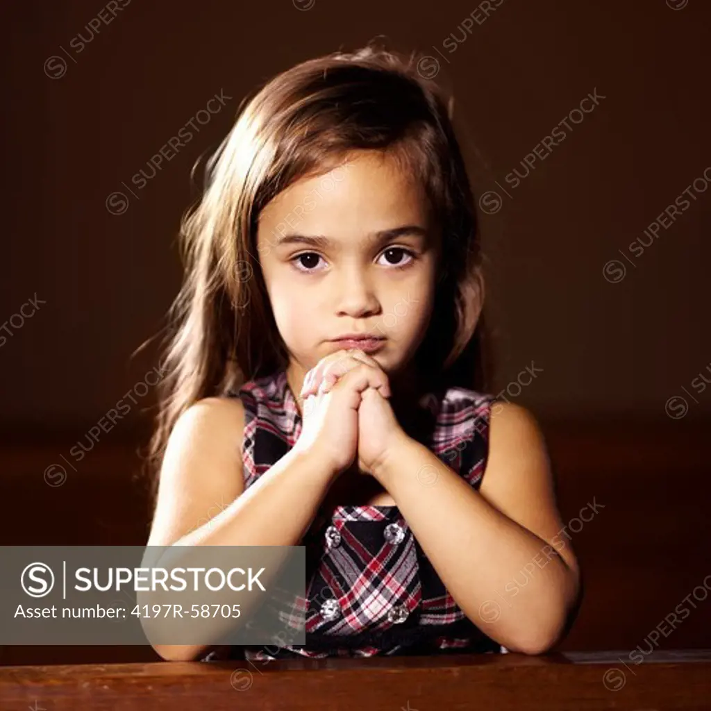 Portrait of a little girl with her hands together while praying in church