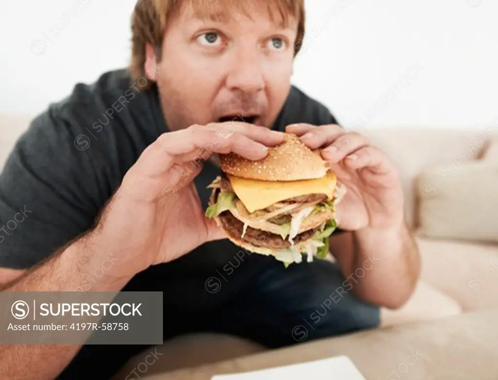 A mature man biting into a hamburger