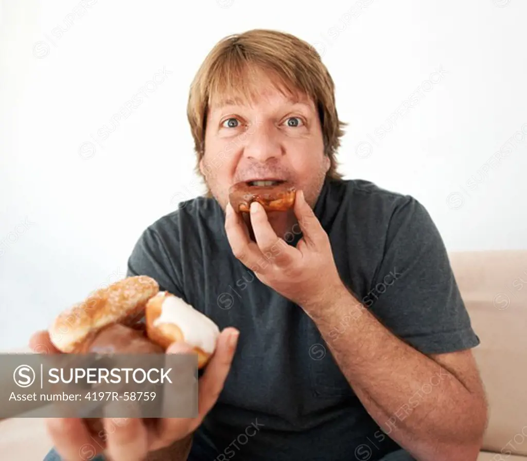 A man biting into a doughnut while looking at the camera