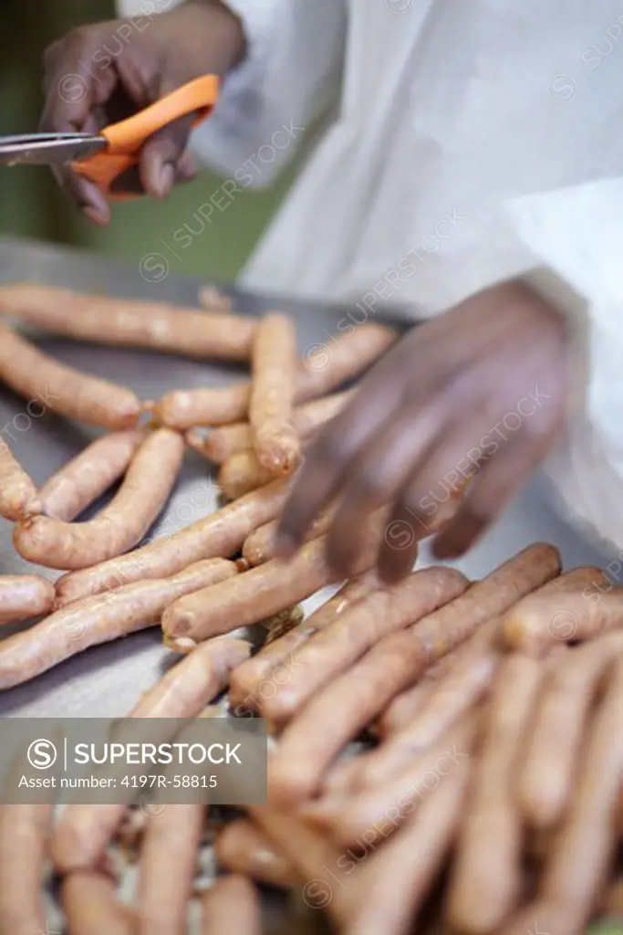 Closeup of a butcher separating sausages by cutting them with a scissor