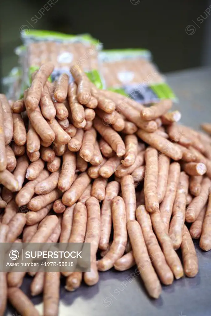Closeup of a pile of sausages with some packaged sausages in the background