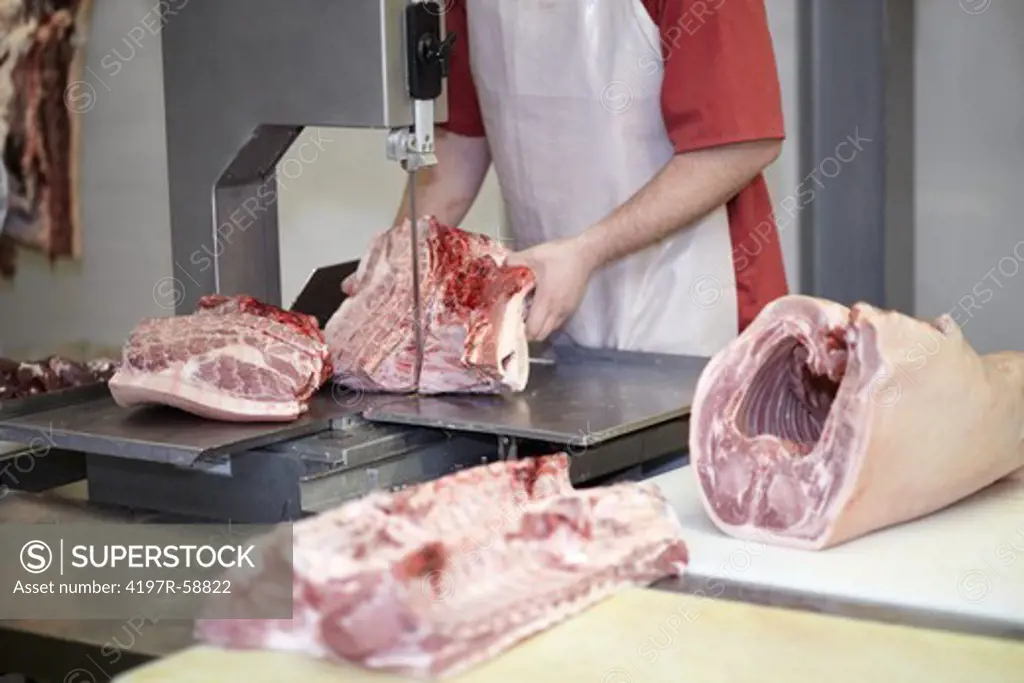 Cropped image of a butcher cutting through a carcass with a meat saw