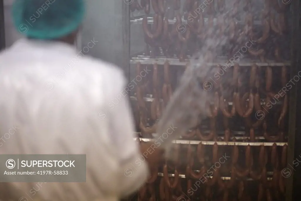 Butcher busy showering a rack of smoked sausages with water