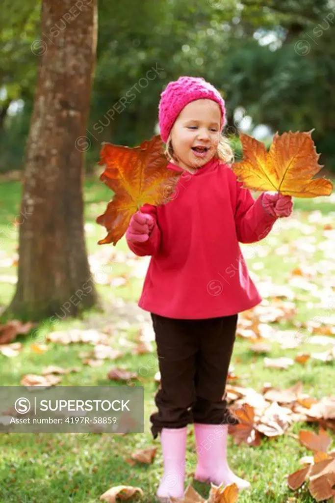 A cute little girl playing with leaves outside