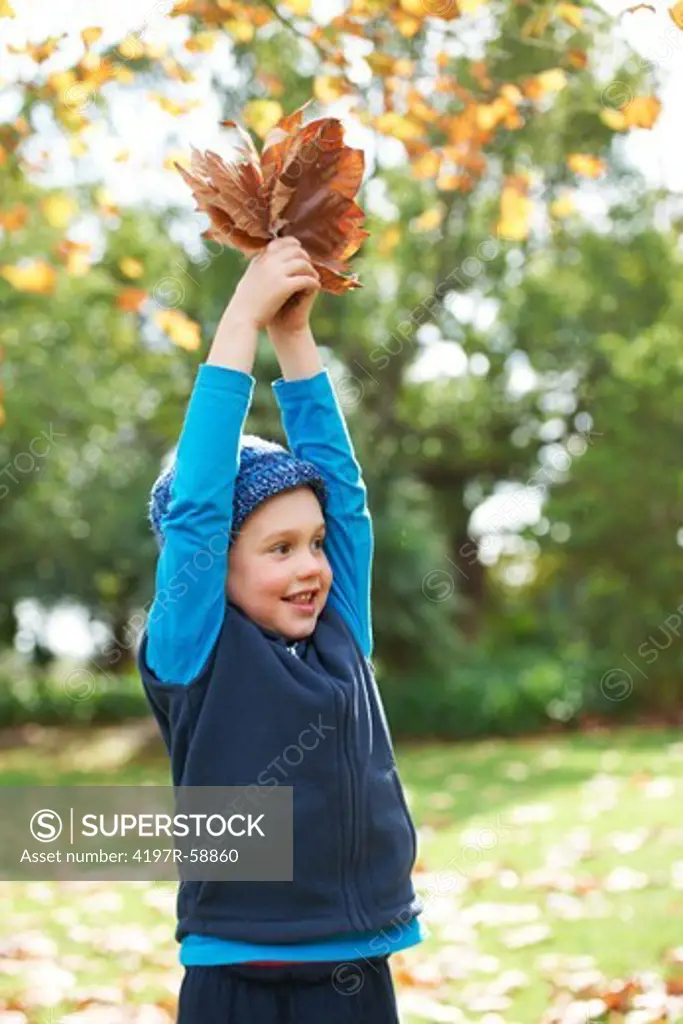 A cute little boy playing with the leaves outside