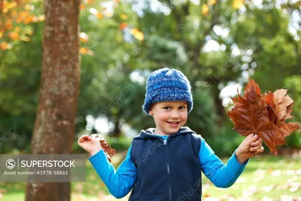 Portrait of a cute little boy playing with the leaves outside