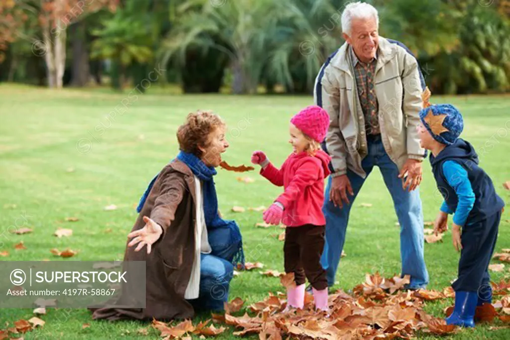 Grandparents playing outside in the leaves with their grandkids