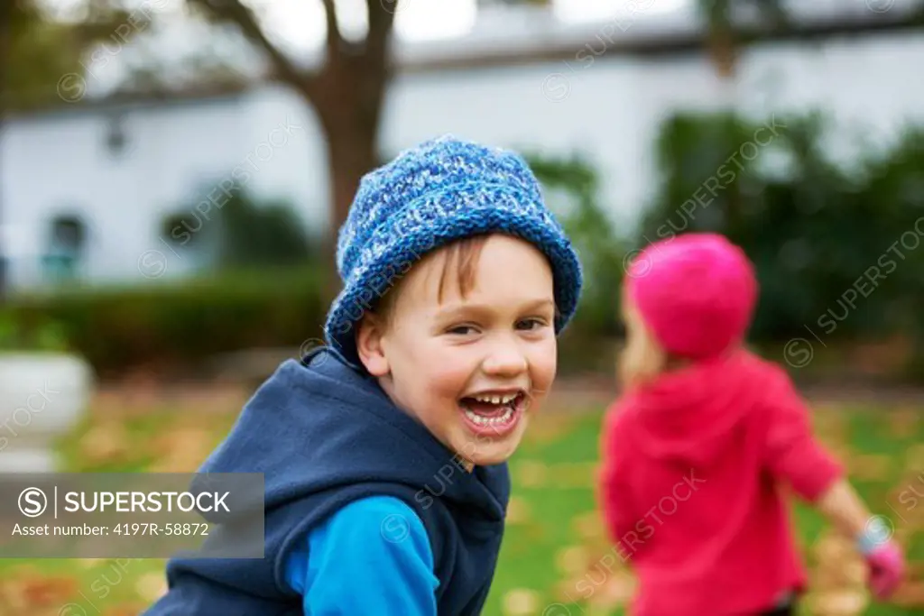 A young boy and his little sister having fun outside