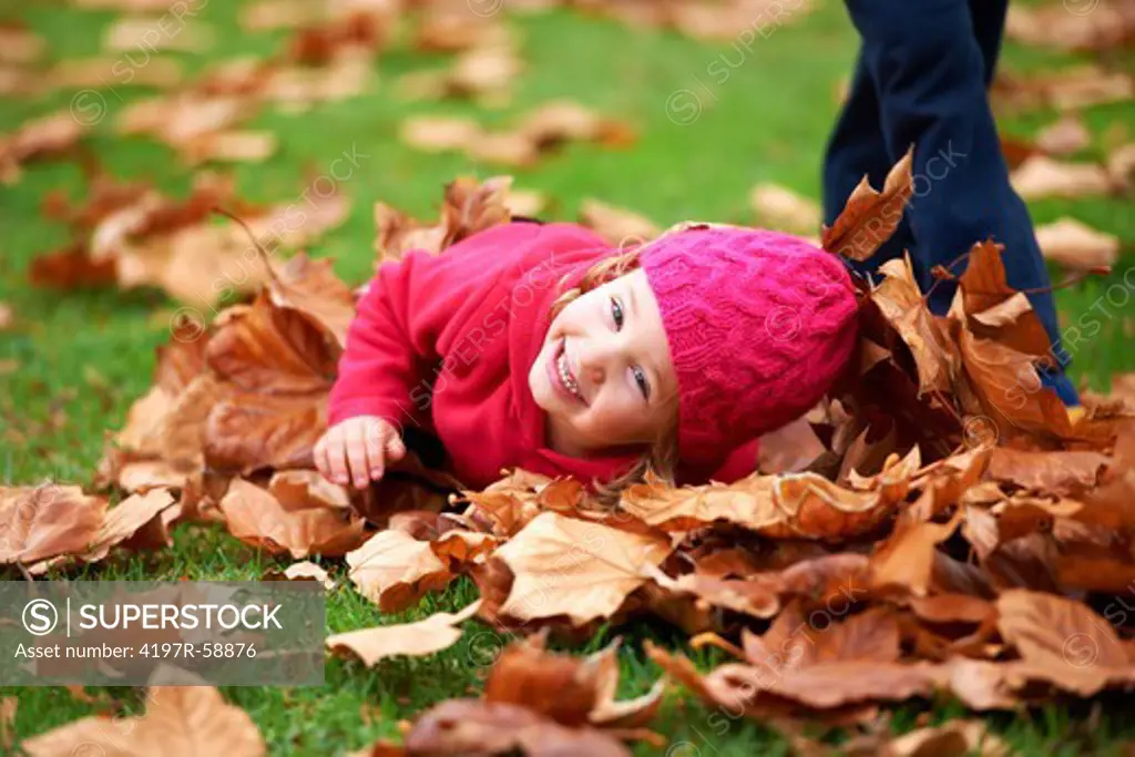 Portrait of a cute little girl laying in the leaves outside