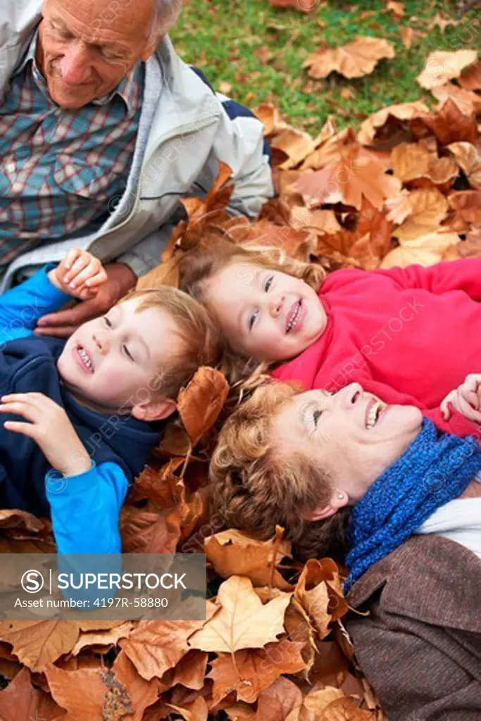 Grandparents lying in the leaves outside with their grandchildren
