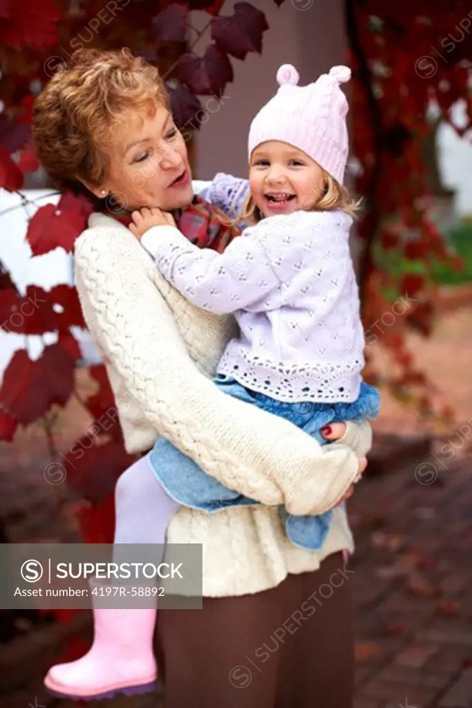 A grandmother holding her granddaughter outside