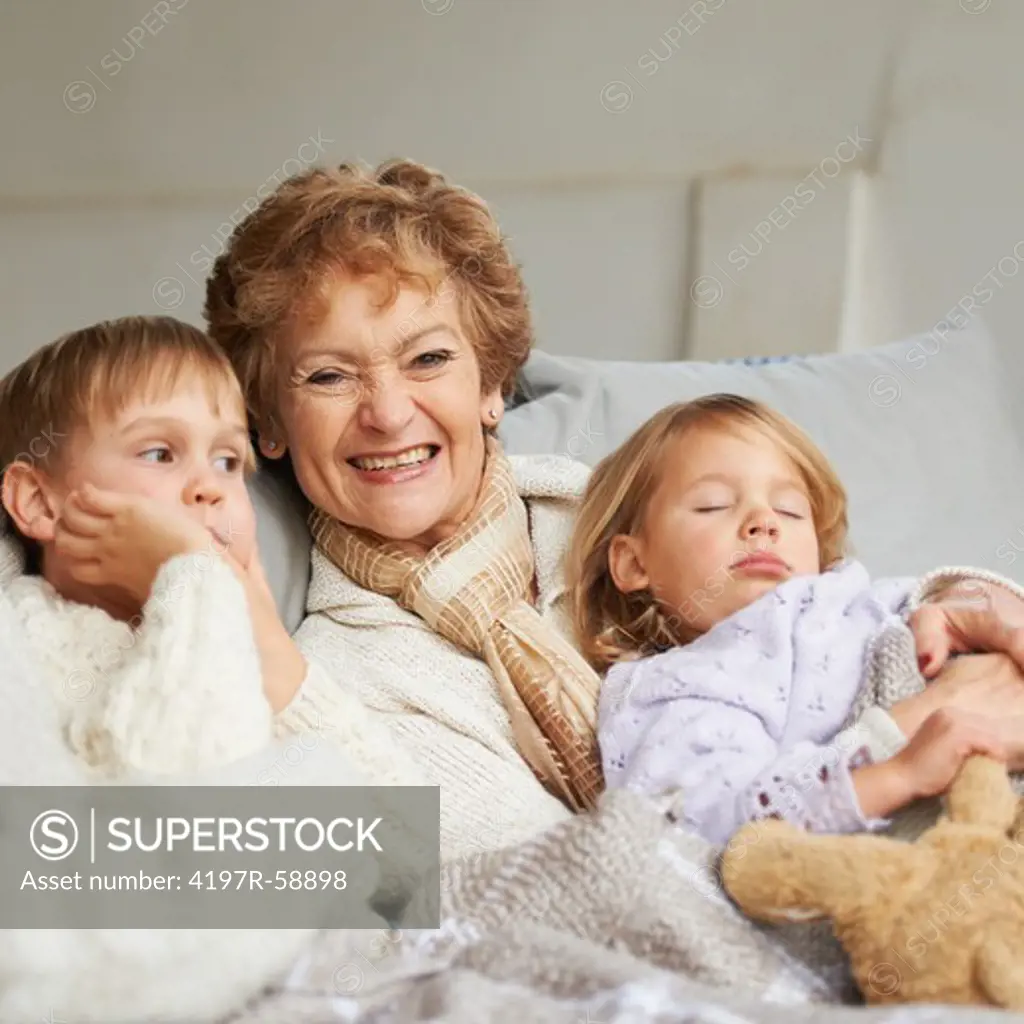 A grandmother sitting on the couch with her grandchildren