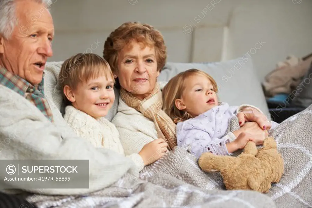Grandparents sitting on the couch with their grandchildren