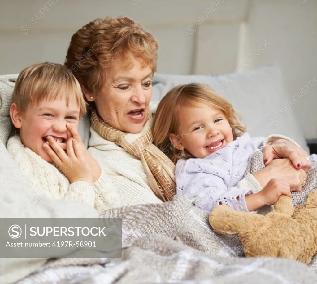 A grandmother relaxing on the couch with her grandchildren