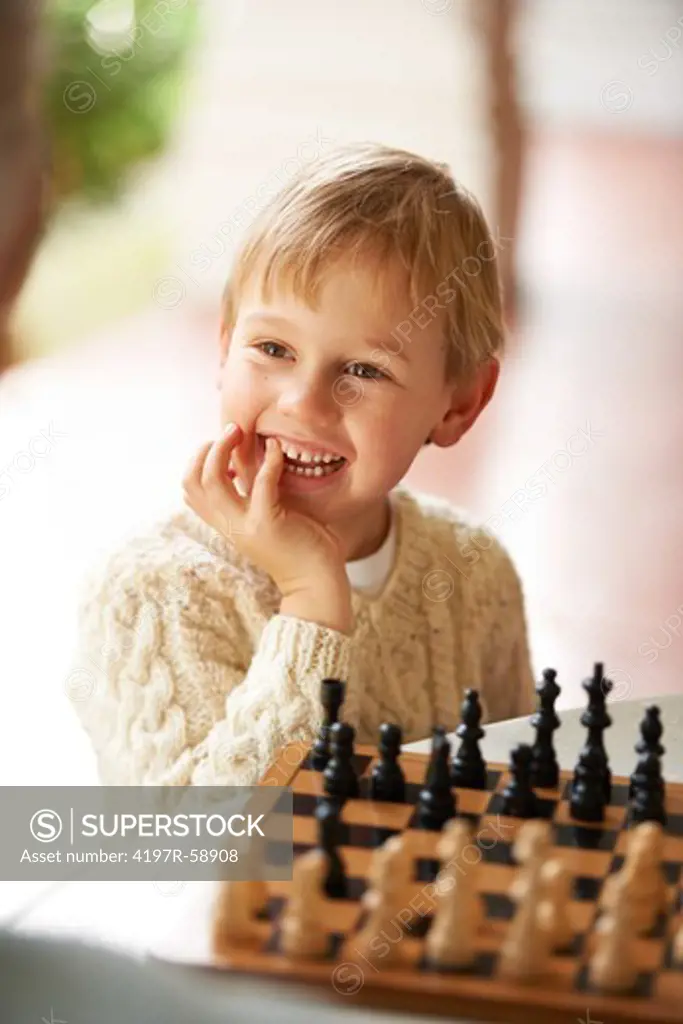A cute little boy sitting and playing chess