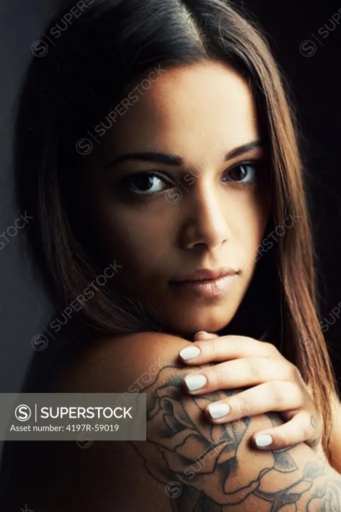 Beautiful young woman gazing at the camera, with a rose tattoo on her shoulder