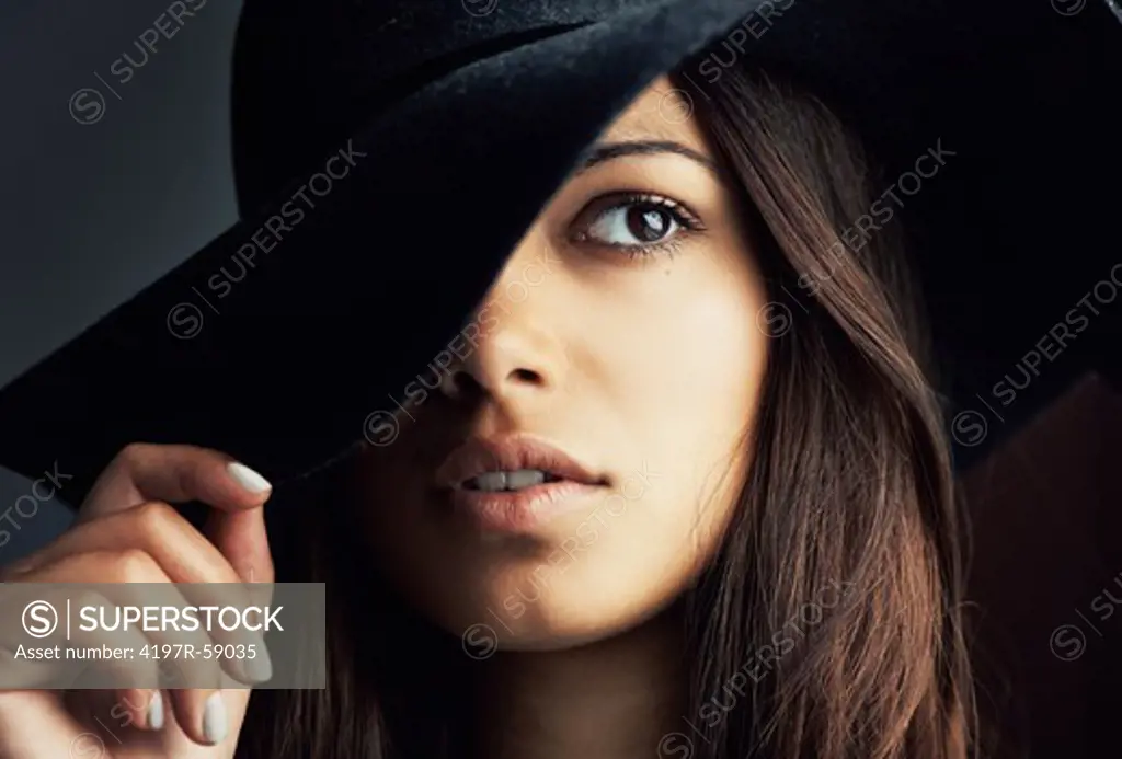 Portrait of a gorgeous young latina woman holding her hat at a sexy angle