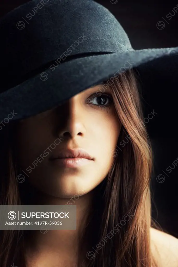 Deeply shadowed portrait of a young hispanic woman wearing a felt hat