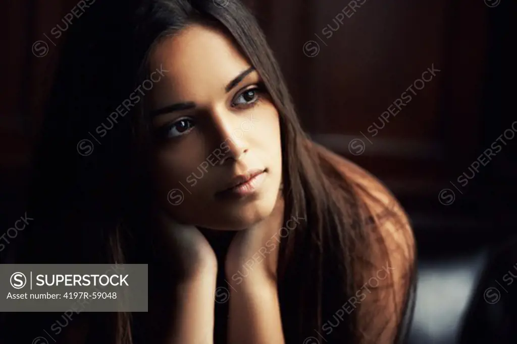 Beautiful latina woman gazing away thoughtfully with a shadowy background
