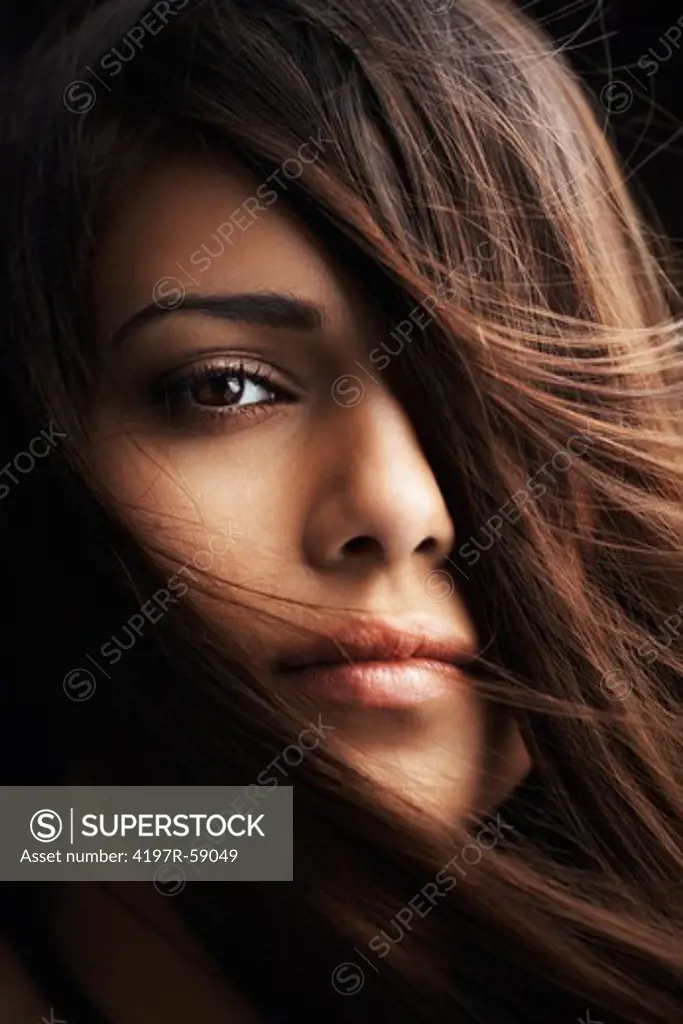 Stunning close up of a woman gazing at you with her hair over half her face