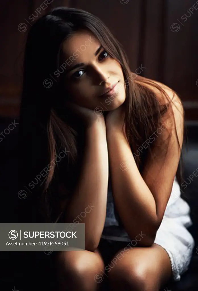 Pretty young latina woman gazing at the camera, resting her chin in her hands