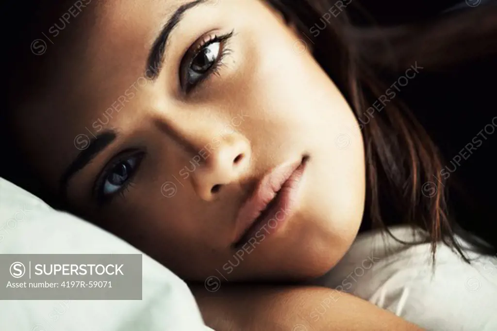 Close up of a gorgeous young latina woman lying on her pillow gazing at you