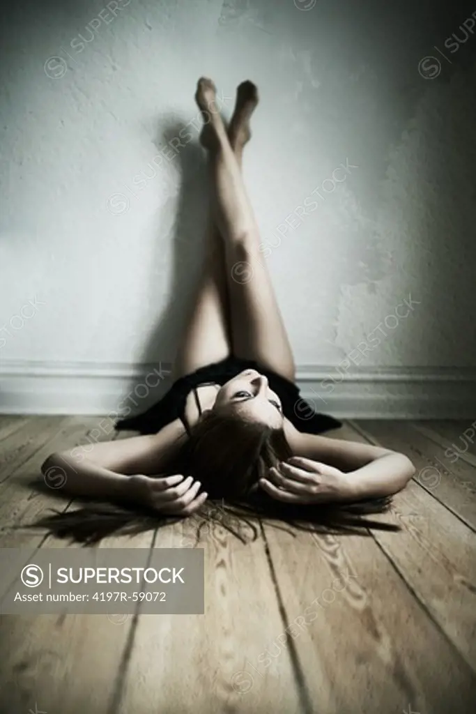 Sensual image of a woman lying on the floor with her legs up against the wall