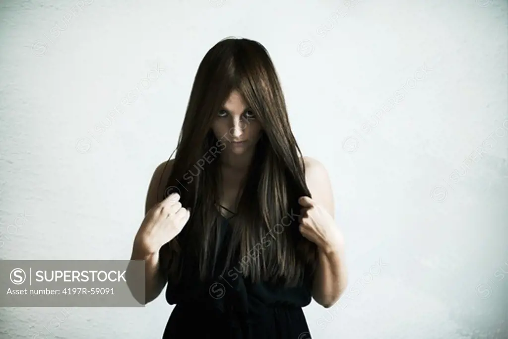Young woman holding her hair to either side and staring at you