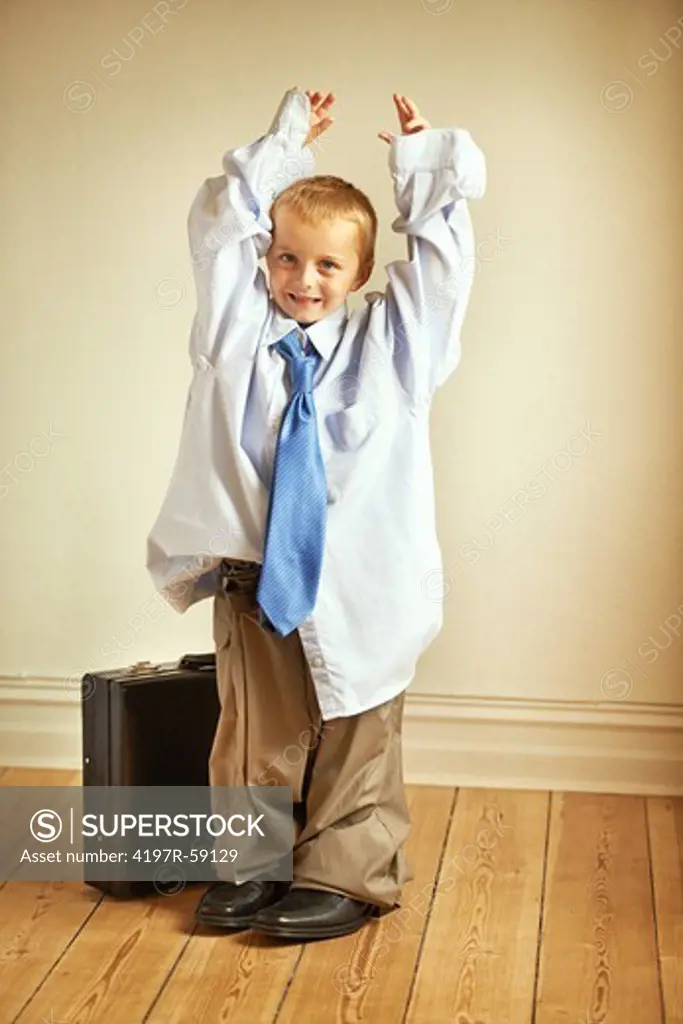 Portrait of a young boy wearing his dad's work clothes and holding a suitcase