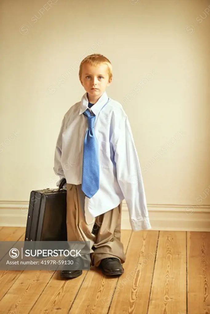 Portrait of a young boy wearing his dad's work clothes and holding