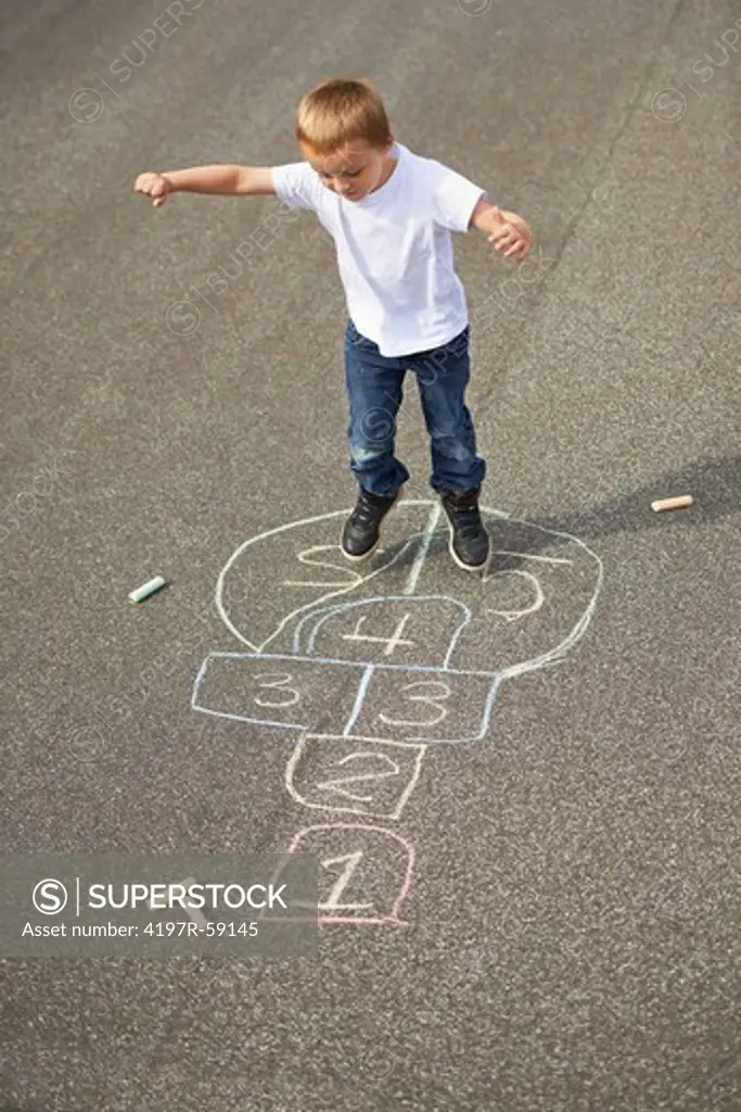A young boy playing hopscotch on the playground